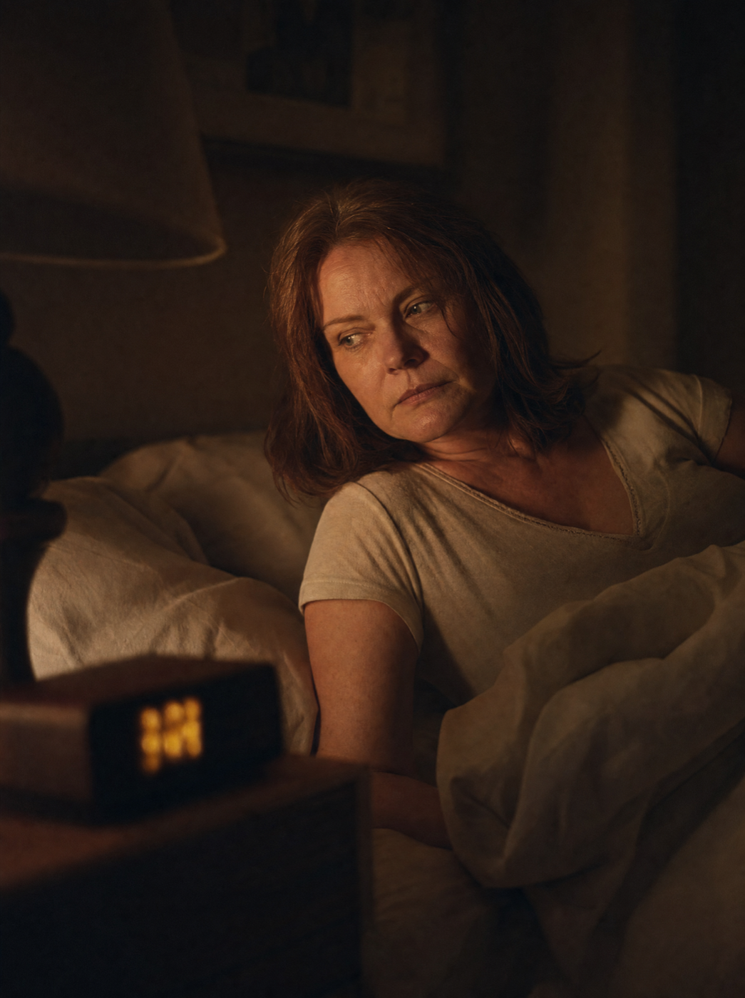 A woman glancing at the clock in the middle of the night, then rolling over to try to fall back asleep